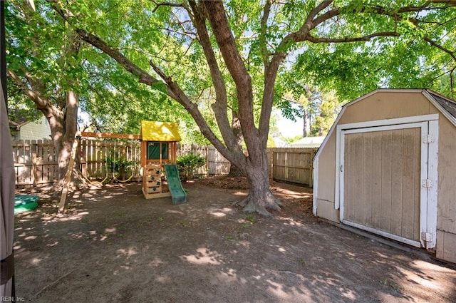 view of yard with an outbuilding, a fenced backyard, a playground, and a storage unit