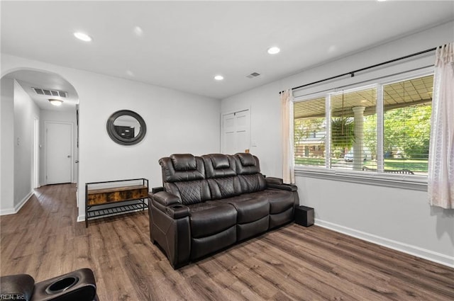 living area featuring arched walkways, wood finished floors, and visible vents