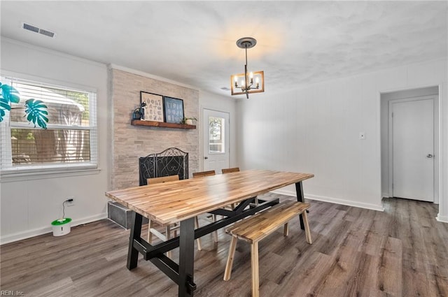 dining area with visible vents, wood finished floors, a fireplace, baseboards, and a notable chandelier