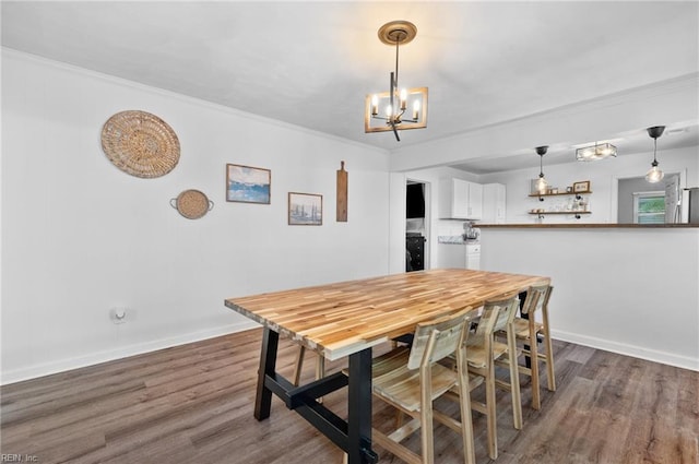 dining area featuring baseboards, ornamental molding, dark wood-type flooring, and a chandelier