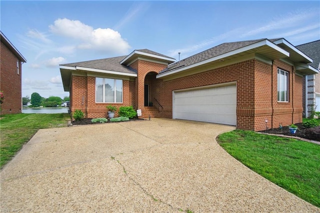 ranch-style home featuring brick siding, a garage, a front yard, a water view, and driveway