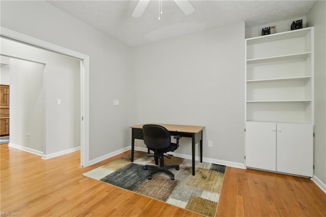 office area featuring a ceiling fan, baseboards, and light wood-type flooring
