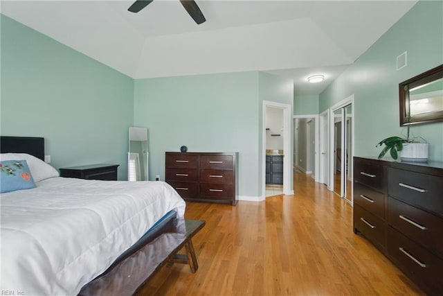 bedroom with light wood-style flooring, a ceiling fan, ensuite bathroom, lofted ceiling, and visible vents
