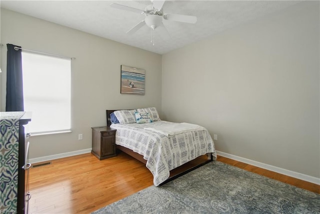 bedroom with baseboards, ceiling fan, and light wood-style flooring