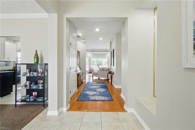hallway with recessed lighting, baseboards, ornamental molding, and light tile patterned floors