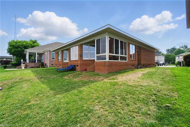 view of side of home with brick siding, a lawn, and crawl space