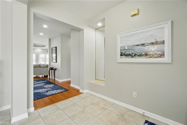 hall featuring recessed lighting, baseboards, and light tile patterned floors