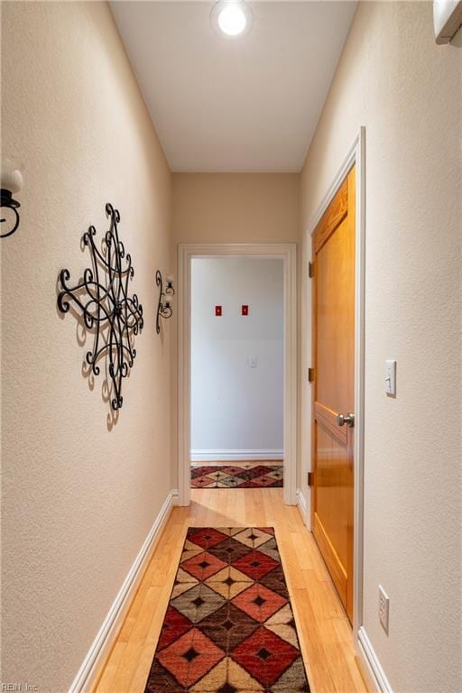 hallway featuring baseboards and light wood finished floors