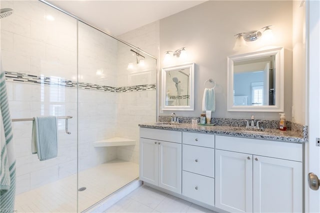 full bath with a sink, a shower stall, and double vanity