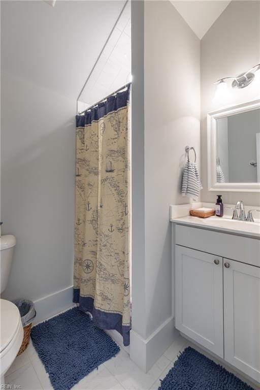 bathroom with curtained shower, vanity, toilet, marble finish floor, and lofted ceiling