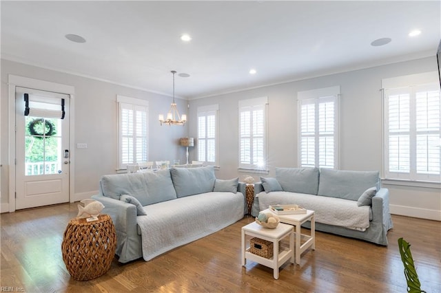 living area with an inviting chandelier, baseboards, crown molding, and wood finished floors