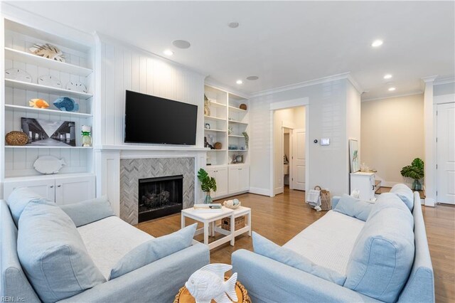 living area with crown molding, baseboards, recessed lighting, a tile fireplace, and light wood finished floors