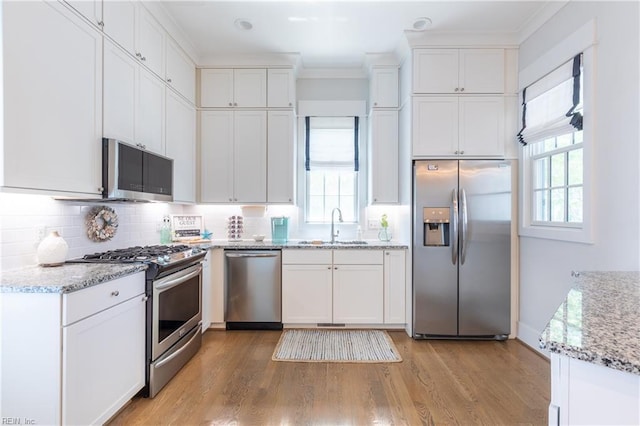 kitchen featuring white cabinets, stainless steel appliances, a sink, and light wood-style floors