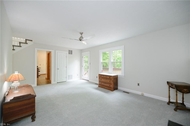 sitting room with ceiling fan, visible vents, baseboards, carpet flooring, and stairs