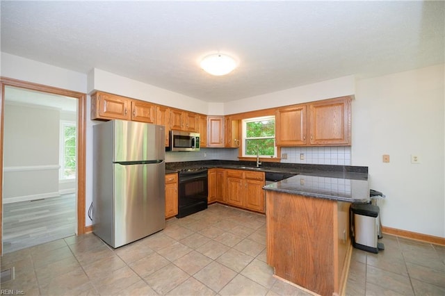 kitchen with appliances with stainless steel finishes, tasteful backsplash, a sink, baseboards, and a peninsula