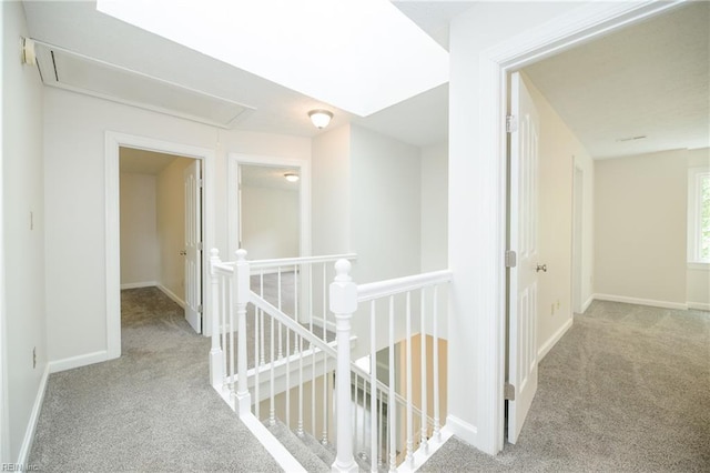 corridor featuring baseboards, an upstairs landing, carpet, and attic access