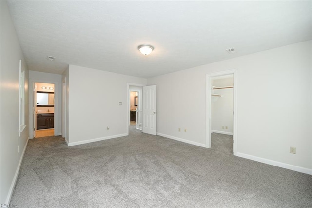 unfurnished bedroom featuring visible vents, carpet floors, baseboards, a spacious closet, and a closet