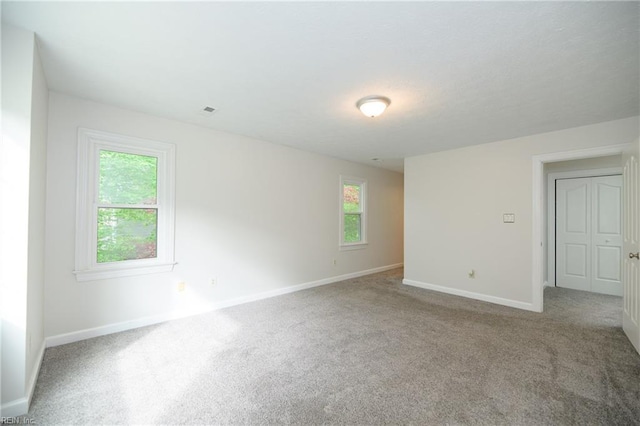 empty room with plenty of natural light, carpet, and baseboards