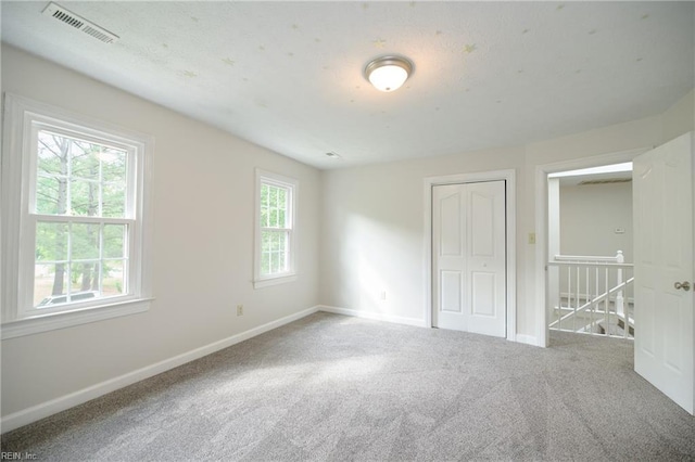 unfurnished bedroom featuring baseboards, carpet, a closet, and visible vents