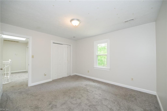 unfurnished bedroom featuring carpet flooring, baseboards, visible vents, and a closet