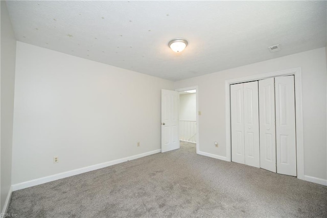 unfurnished bedroom featuring carpet floors, baseboards, and a closet