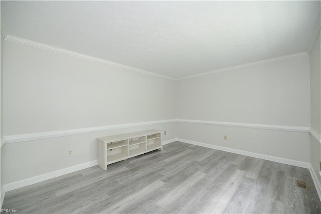 unfurnished room with crown molding, baseboards, wood finished floors, and visible vents