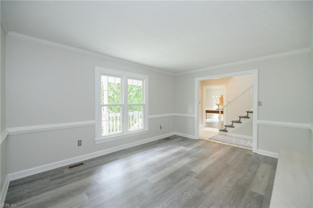 spare room featuring visible vents, crown molding, stairs, wood finished floors, and baseboards