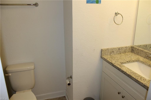 bathroom featuring toilet, baseboards, and vanity