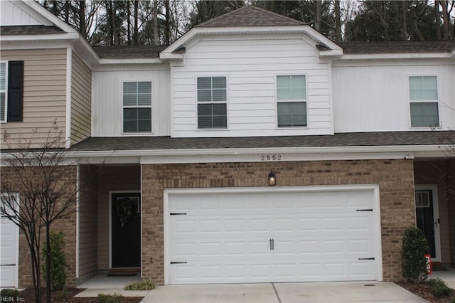 view of front facade with brick siding, an attached garage, and driveway