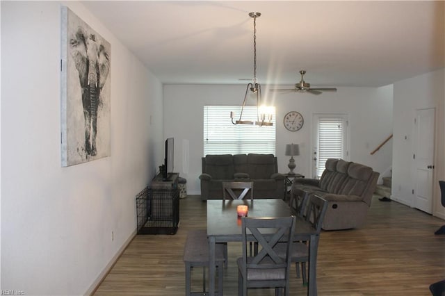 dining space featuring stairway, baseboards, ceiling fan with notable chandelier, and wood finished floors