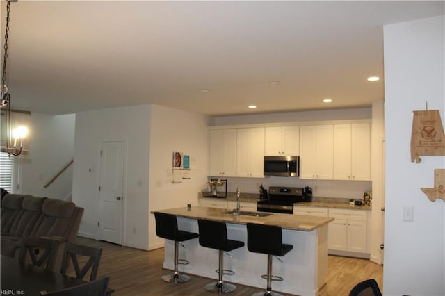 kitchen featuring a sink, light wood finished floors, appliances with stainless steel finishes, and a breakfast bar area