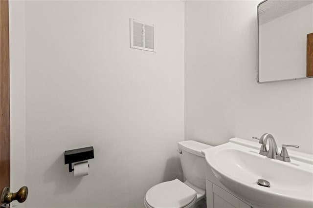 bathroom with visible vents, toilet, and vanity