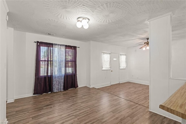 foyer with a ceiling fan, baseboards, visible vents, and wood finished floors