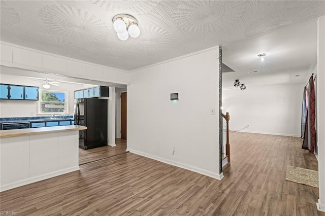 unfurnished living room featuring baseboards, ceiling fan, a sink, and wood finished floors
