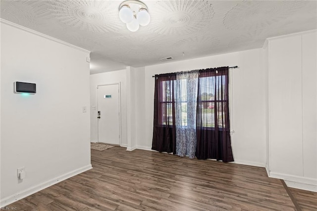 empty room featuring baseboards, visible vents, and wood finished floors