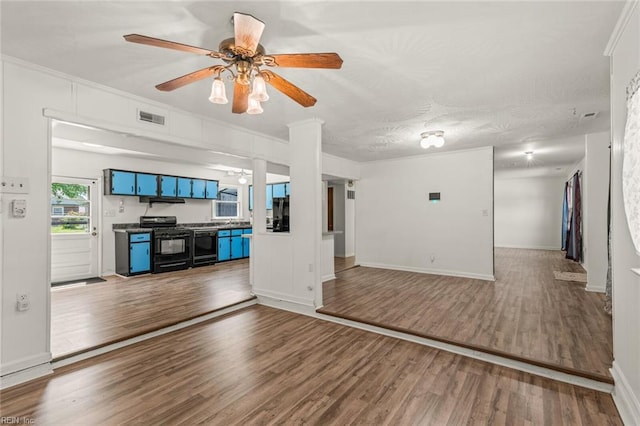 unfurnished living room featuring visible vents, crown molding, wood finished floors, baseboards, and a ceiling fan