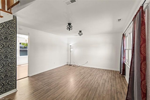 spare room featuring baseboards, visible vents, and wood finished floors
