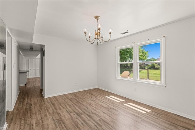 unfurnished room featuring a chandelier, baseboards, visible vents, and wood finished floors