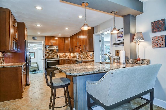 kitchen featuring decorative backsplash, stainless steel appliances, a peninsula, and under cabinet range hood