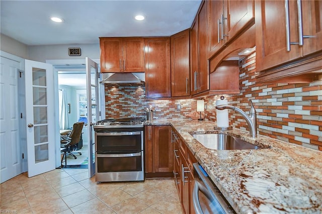 kitchen with brown cabinetry, french doors, appliances with stainless steel finishes, a sink, and under cabinet range hood