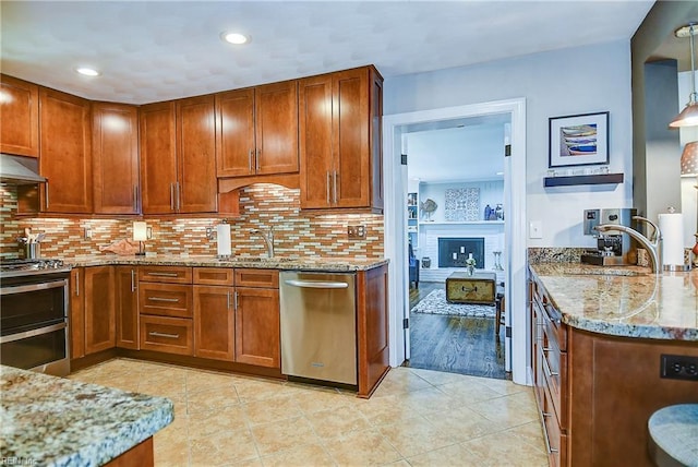 kitchen featuring light stone counters, brown cabinetry, appliances with stainless steel finishes, and light tile patterned floors