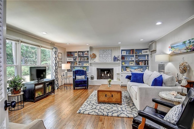 living room featuring recessed lighting, ornamental molding, wood finished floors, and a fireplace