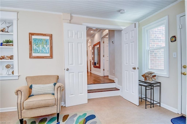 living area with crown molding, carpet floors, and baseboards