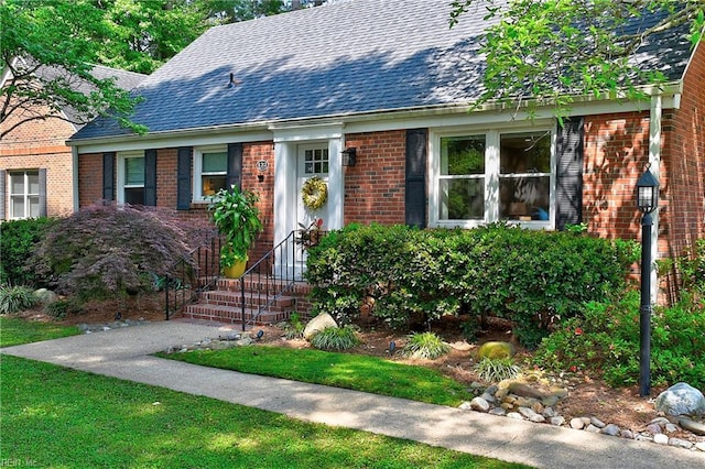 view of front of home with a shingled roof and brick siding