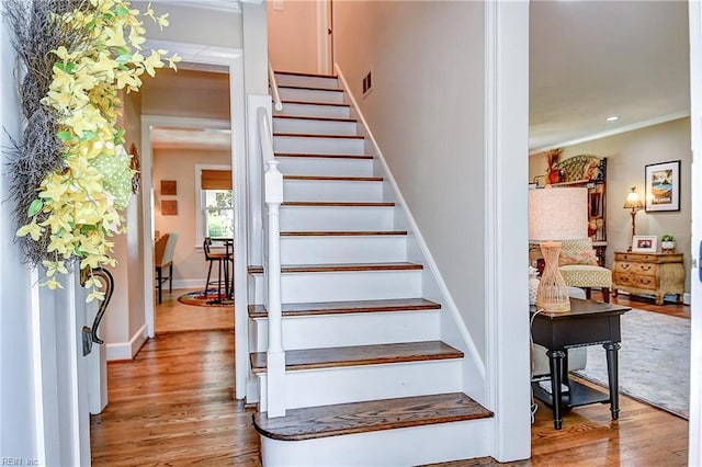 staircase with visible vents, ornamental molding, wood finished floors, baseboards, and recessed lighting
