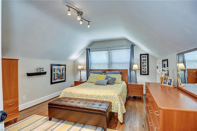 bedroom featuring baseboards, multiple windows, wood finished floors, and lofted ceiling