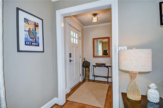 foyer featuring baseboards, ornamental molding, and wood finished floors