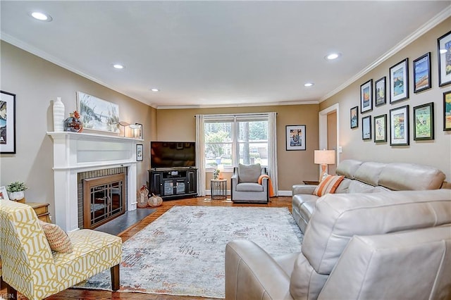 living area with crown molding, a brick fireplace, recessed lighting, and wood finished floors