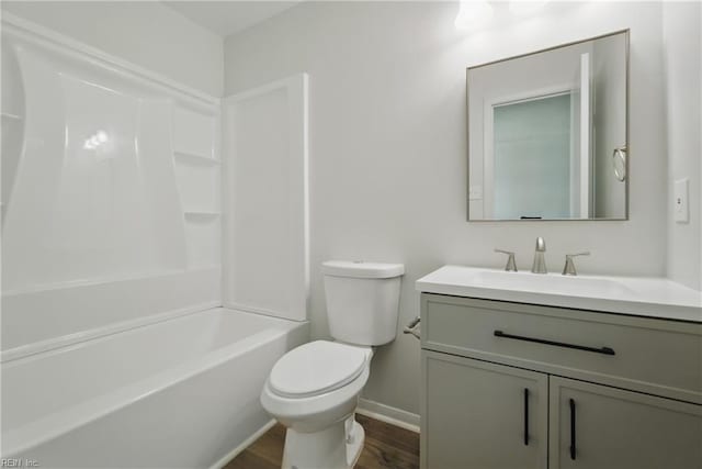 full bathroom with vanity, wood finished floors, toilet, baseboards, and shower / washtub combination