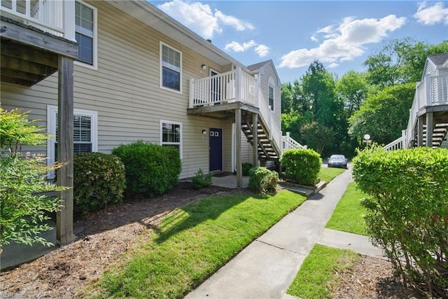 exterior space with stairs, a lawn, and a wooden deck